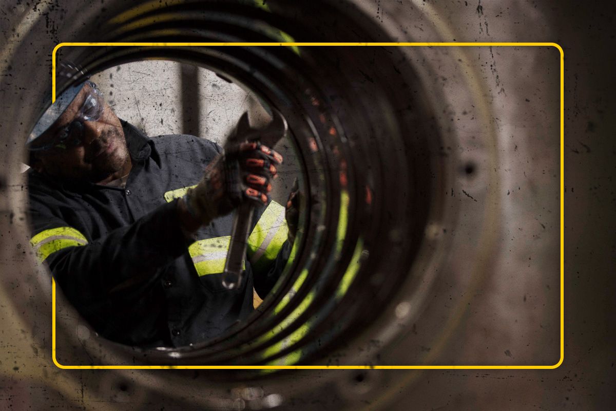 View of a Cat worker wearing PPE servicing an SPM part through a large metal tube