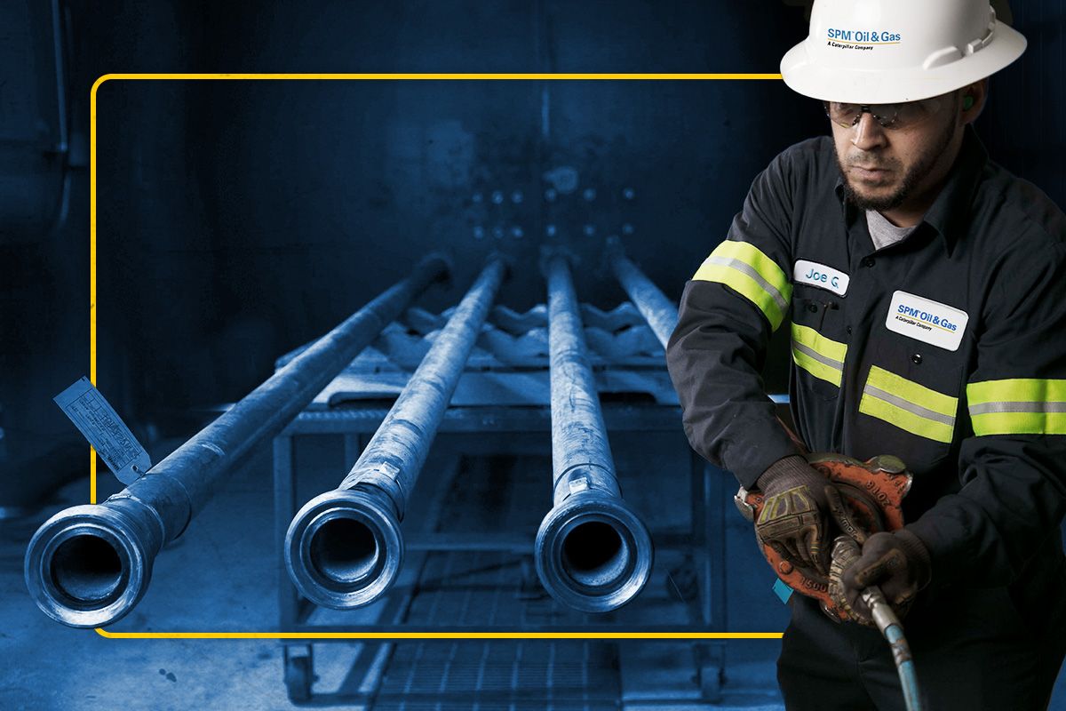 Cat worker in PPE attaching a SPM fixture to a pipe next to a row of pipes shaded in blue
