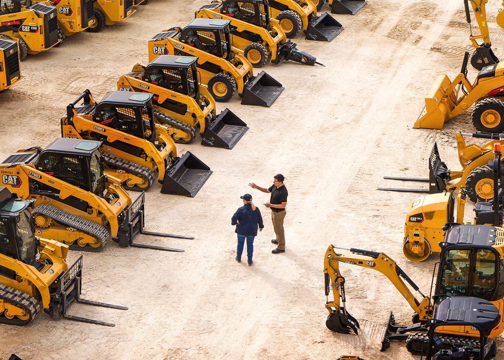 dealer and customer looking at a large lineup of Skid Steer Loaders