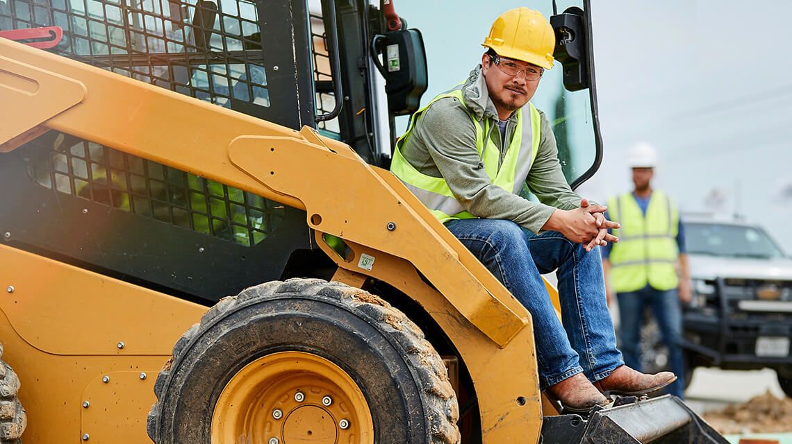 Construction worker, with hardhat, sitting on Cat machine