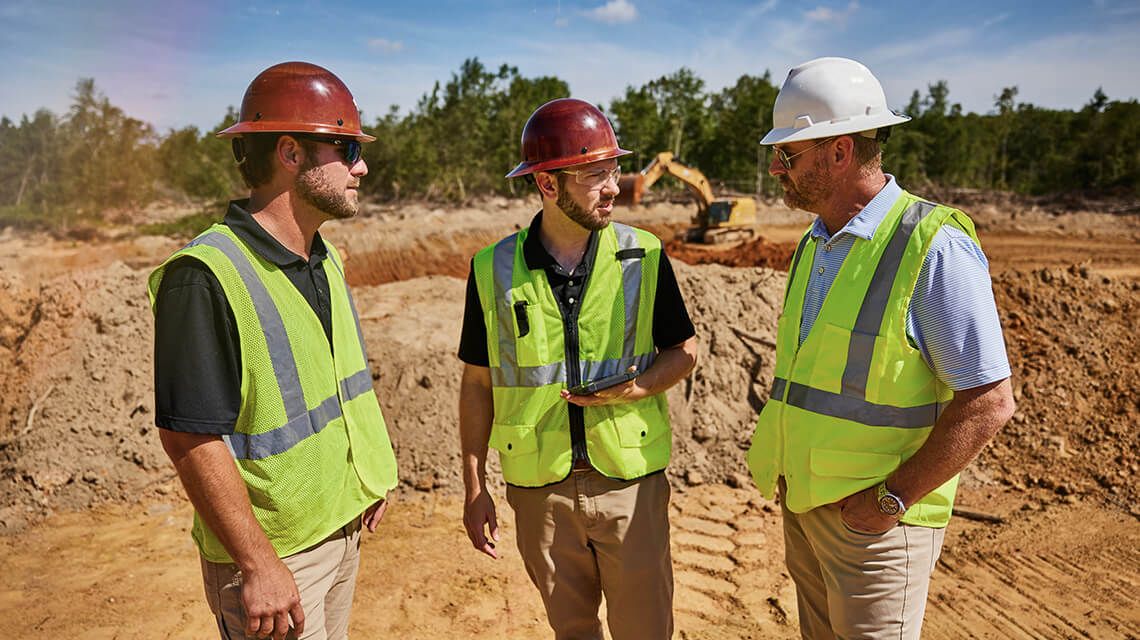 Three construction workers talking together on a jobsite
