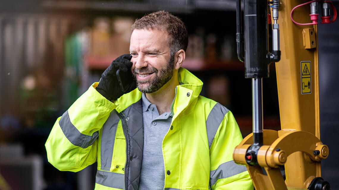 Person wearing a safety jacket talking on a phone and smiling