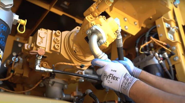 Technician performing maintenance on a hydraulic pump