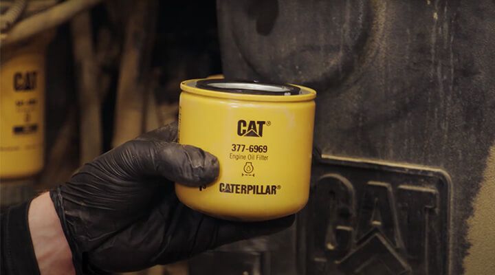 Technician changing spin-on engine oil filter on equipment 